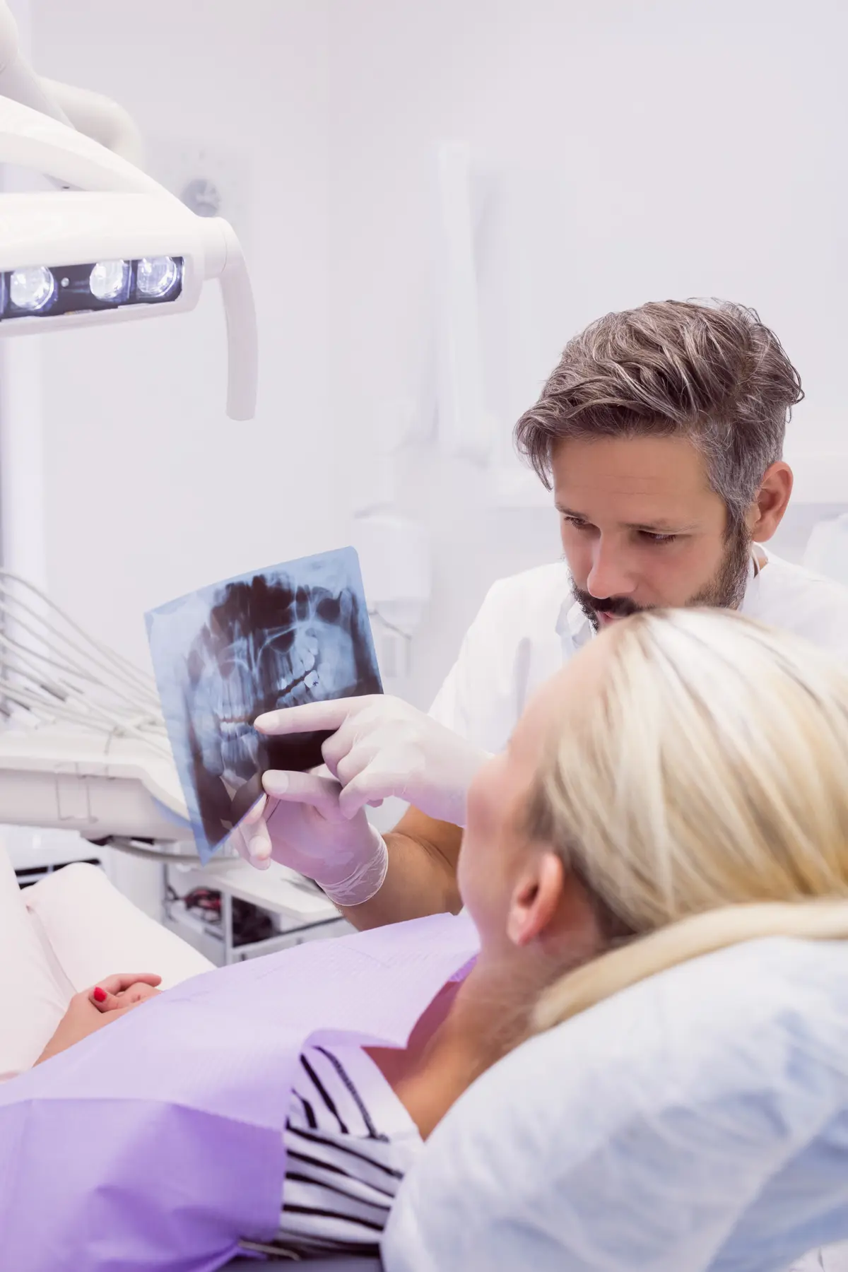 Dos profesionales repasando una radiografía con un paciente mayor